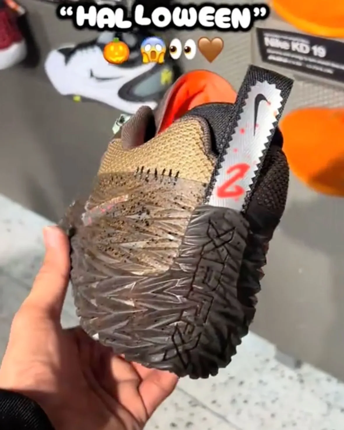 In-hand heel view with serrated white tab, red 2 and orange lining, emoji overlay, Halloween