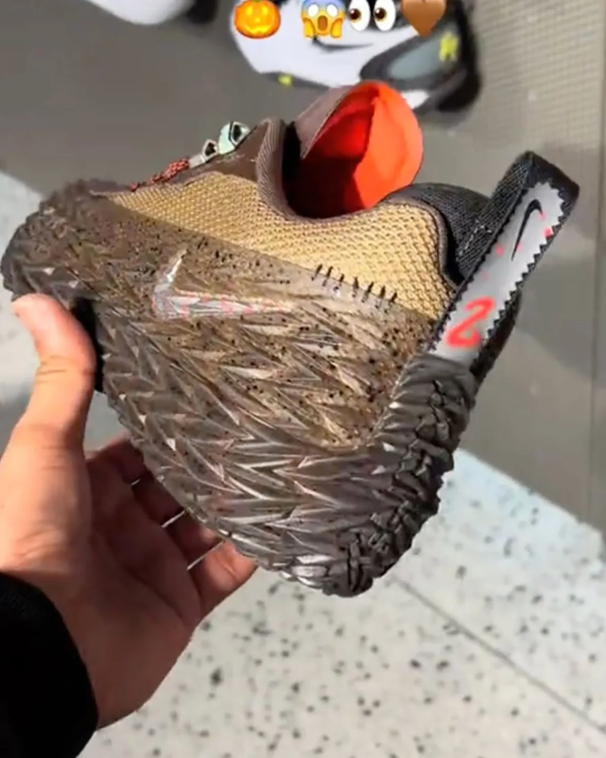 In-hand shot of shoe on its side, spiky sole, chainsaw-style heel tab, emoji overlay, Halloween