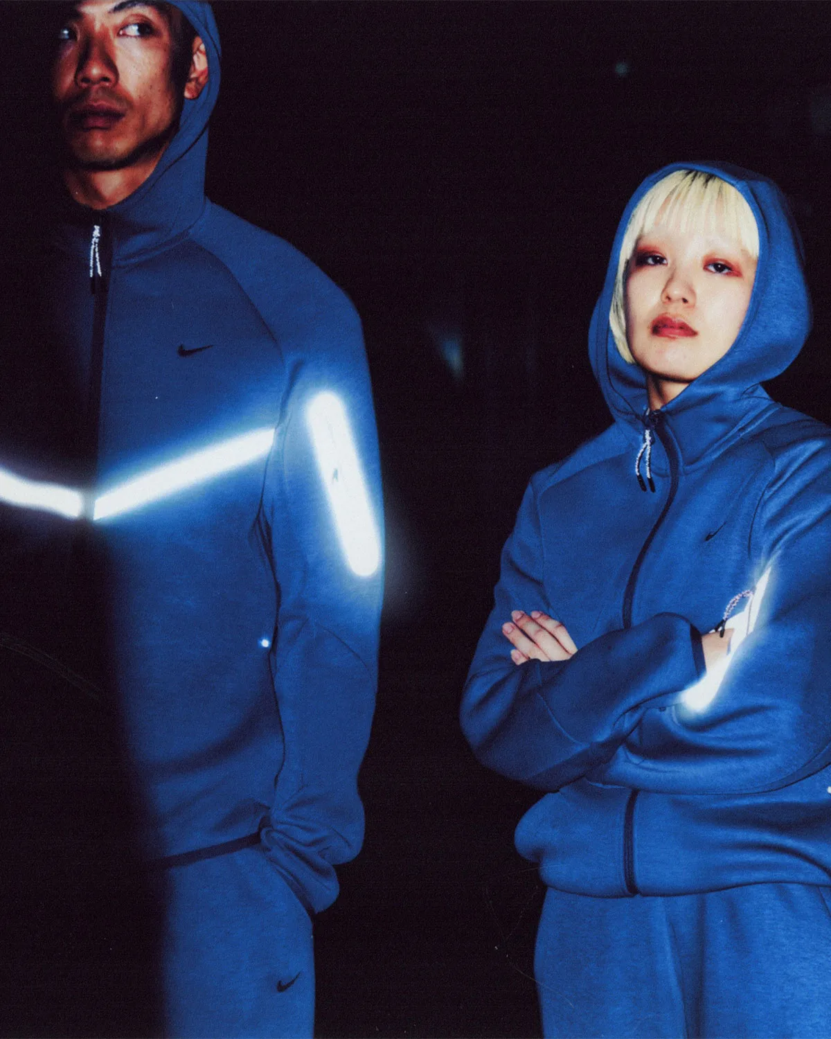 Two people in blue hoodies at night, glowing reflective chevron and sleeve stripes, Boreas and SF3