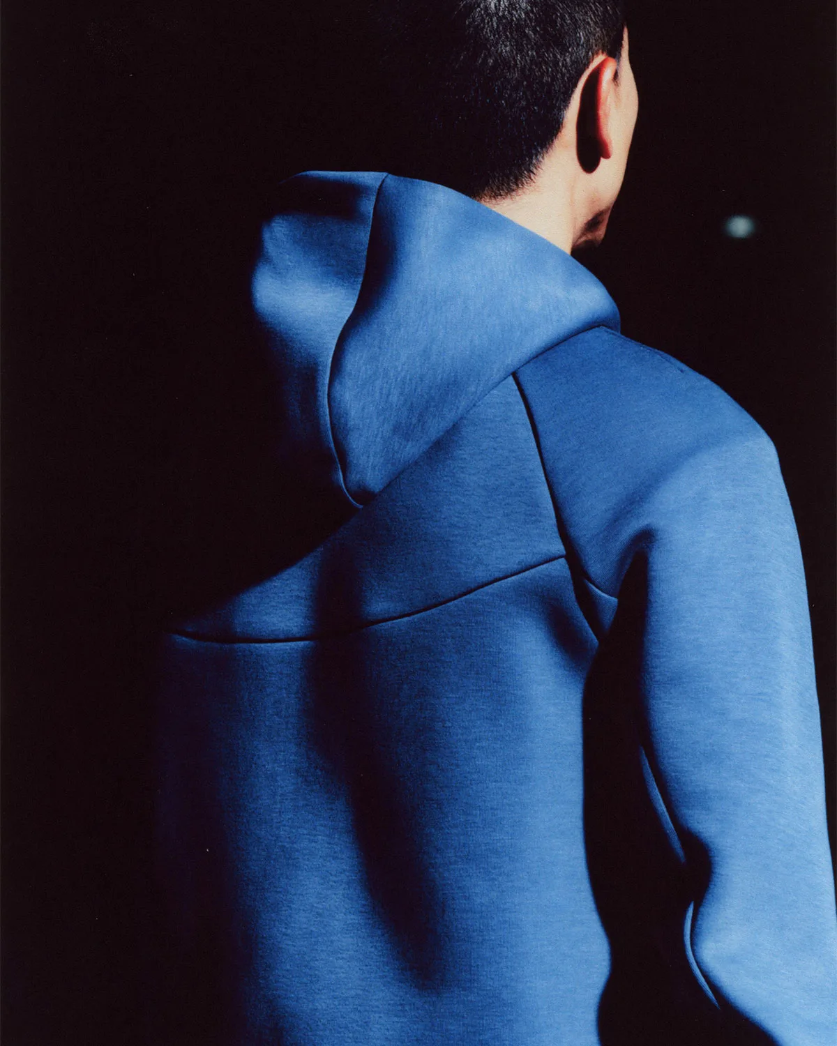 Rear view of person in blue hoodie, seamed back panel against dark background, Boreas and SF3