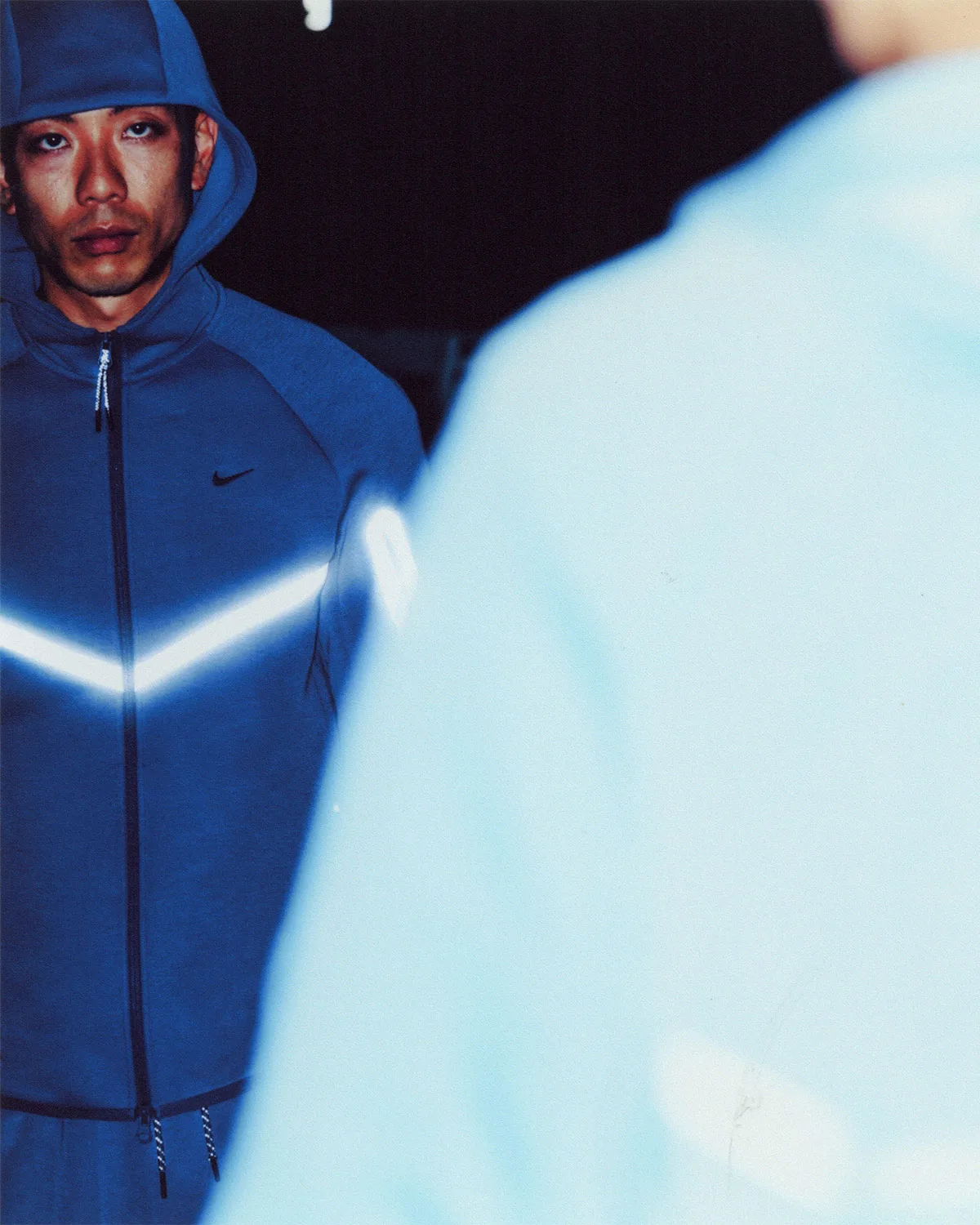 On-foot close shot, blue hoodie with glowing chevron beside blurred pale blue foreground, Boreas and SF3