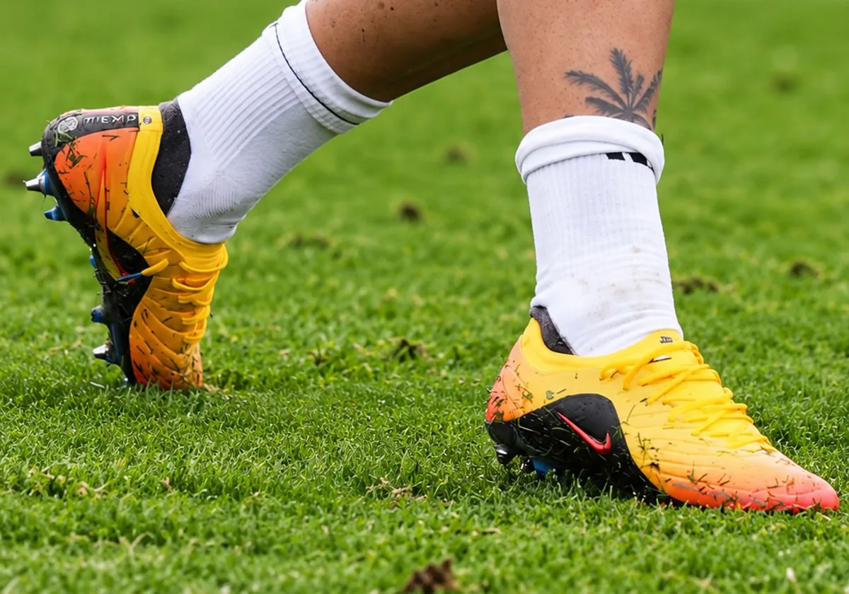 Pair on grass, one boot heel-up with Tiempo text, other lateral with red swoosh, white socks, Sundial