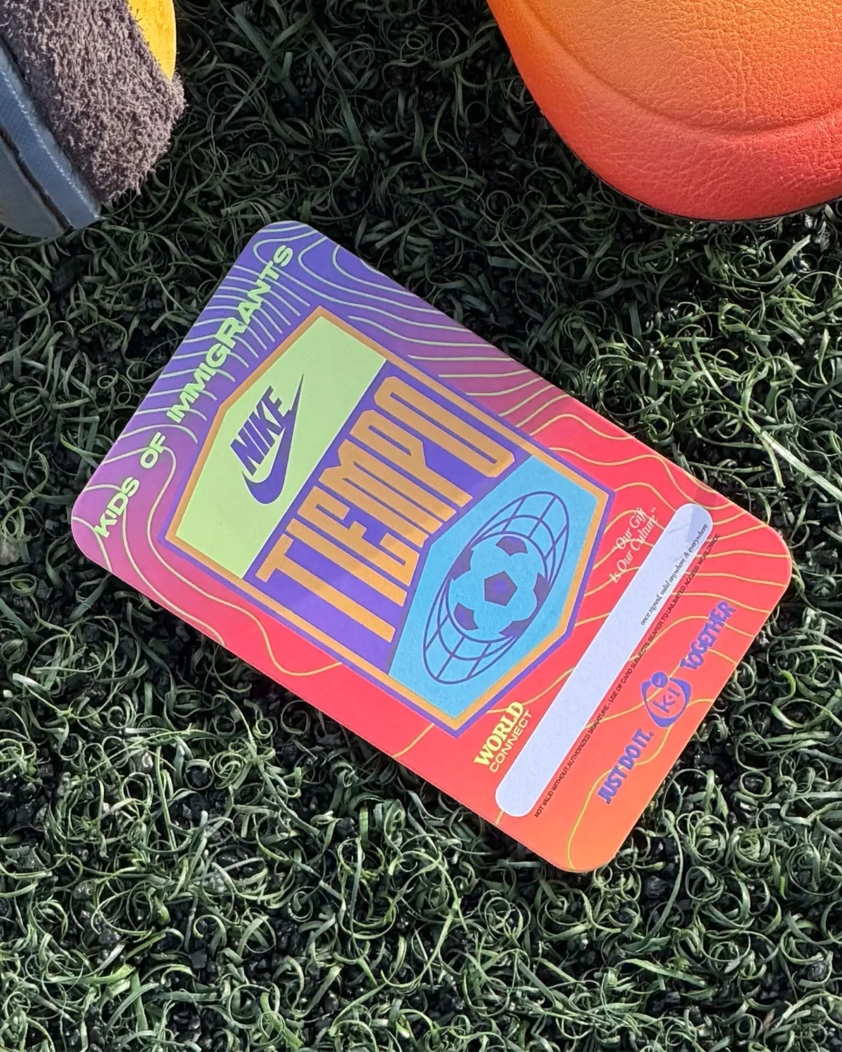 Top-down of rainbow-gradient Tiempo card with globe-ball graphic on turf, shoe parts at top edge, Amarillo