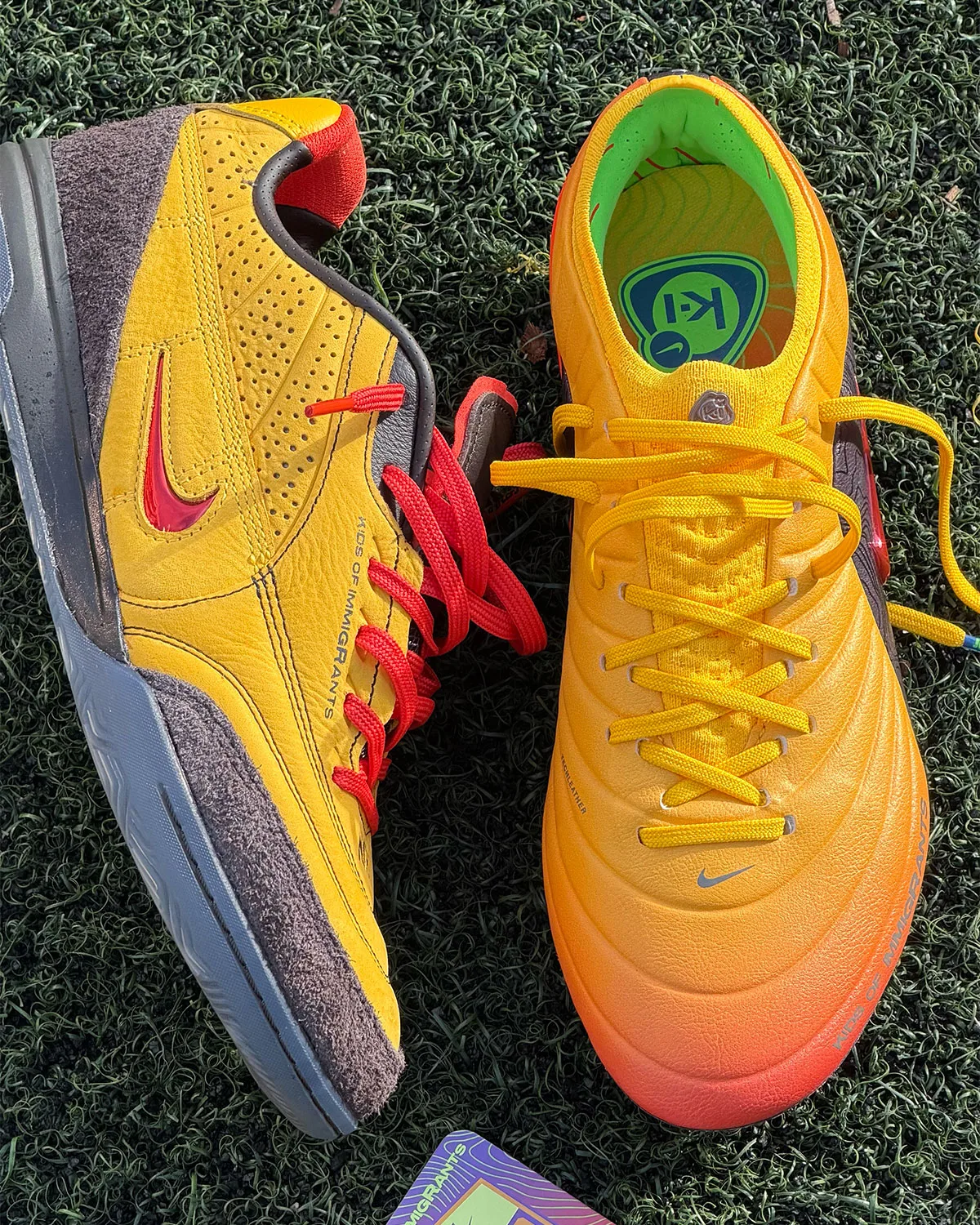 Top-down pair on turf: yellow suede lateral with red swoosh beside orange-gradient shoe with yellow laces, Amarillo