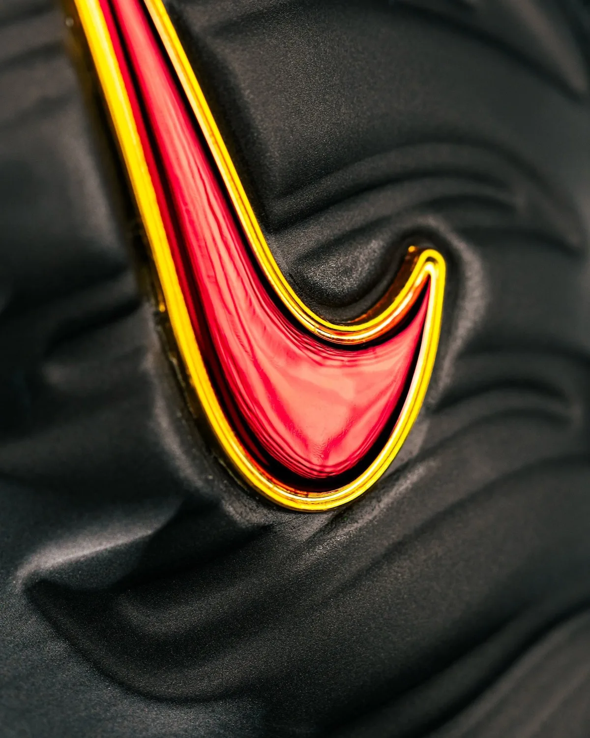 Close-up of glossy red swoosh with gold outline on textured black upper, Pro USC PE