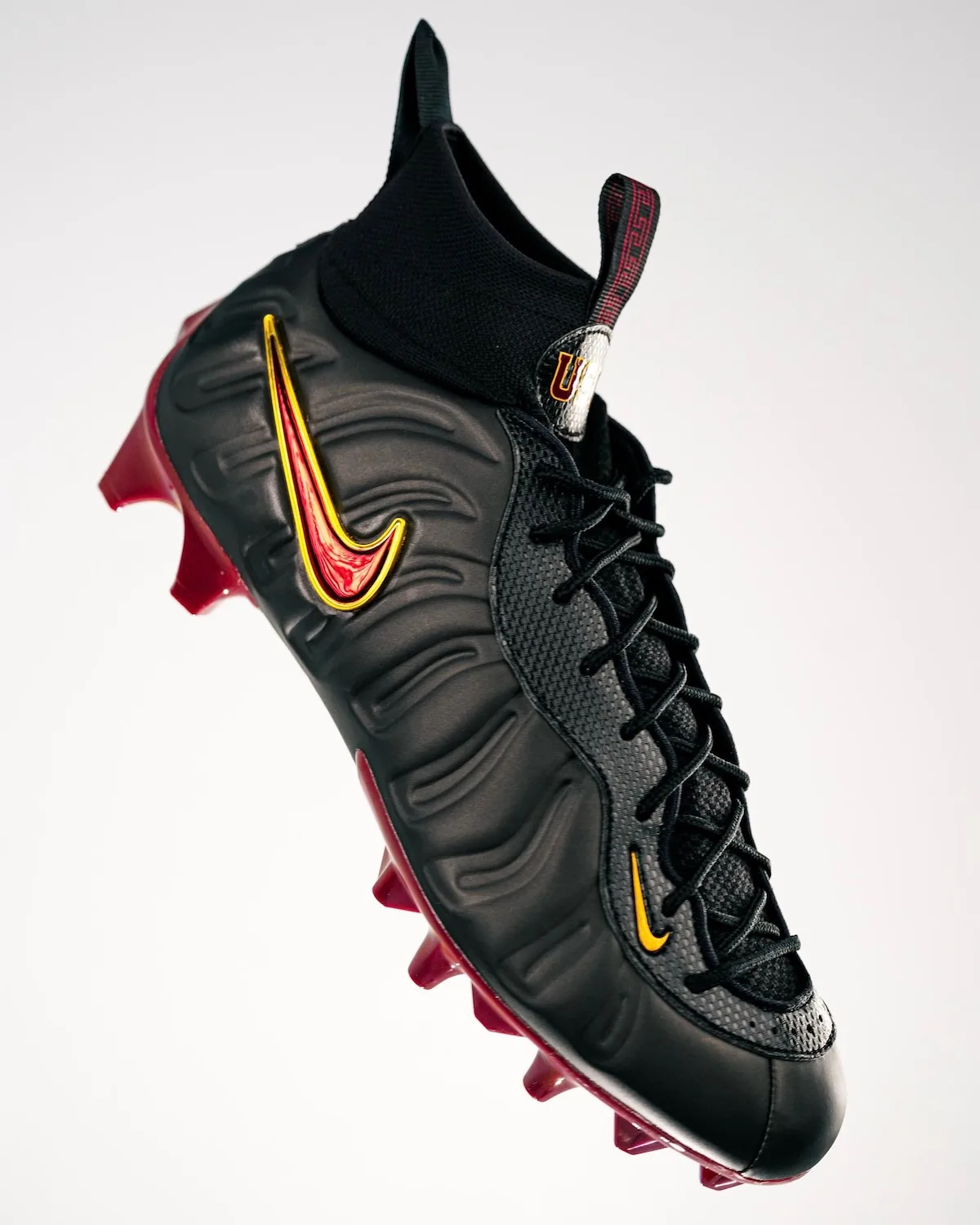 Lateral view of black high-top cleat with red-gold swoosh, black laces, maroon studs and a USC tab, Pro USC PE