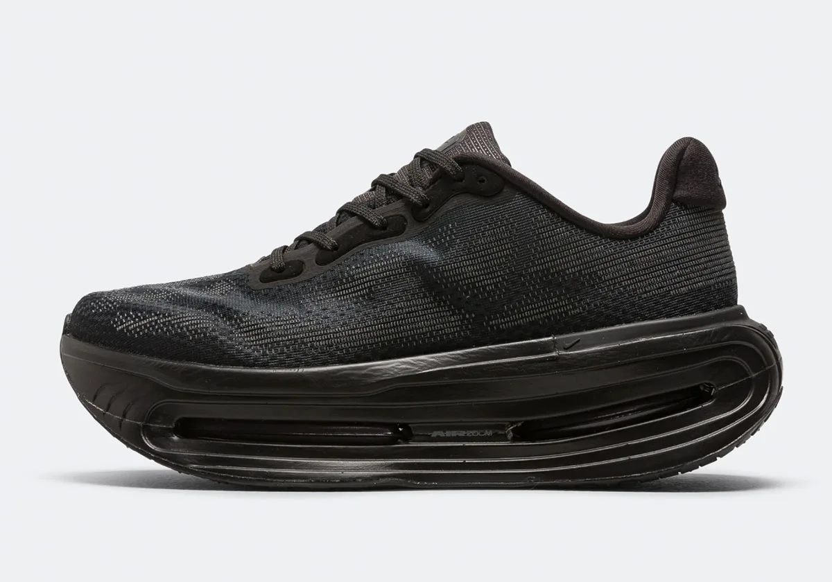 Lateral view of all-black knit sneaker with tall midsole, visible Air Zoom unit and text, Skeleton