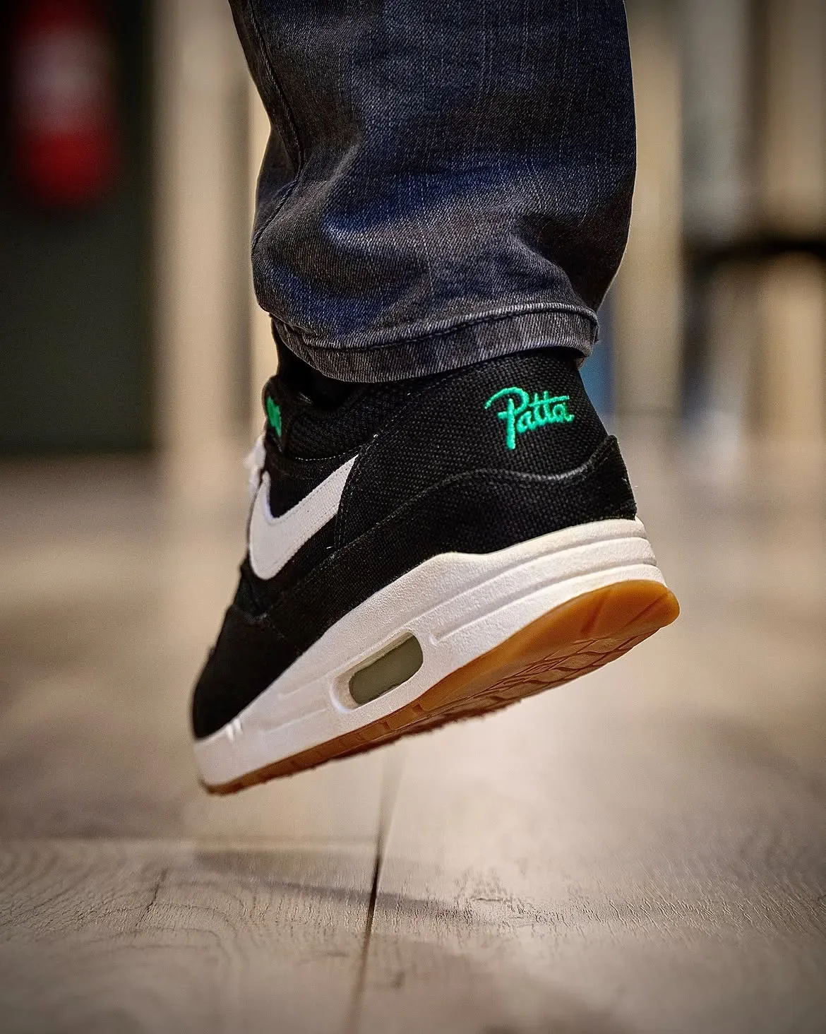 on-foot heel close-up, green Patta script above white swoosh, gum outsole tread, Lucky Green
