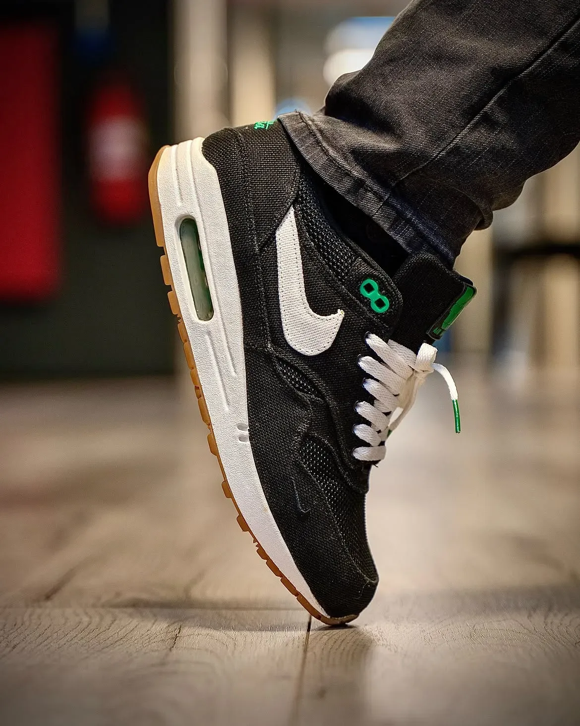 on-foot lateral toe close-up, white swoosh, green 08 tab, gum outsole, wood floor, Lucky Green