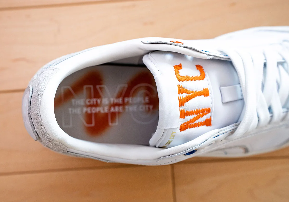 Close-up of orange NYC embroidered tongue and grey insole with faint NYC text and orange spray, Ceremony