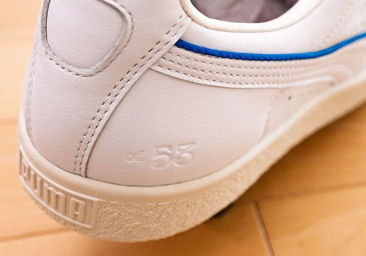 Heel detail of white leather with embossed "of 53" text and blue stripe above cream sole, Ceremony