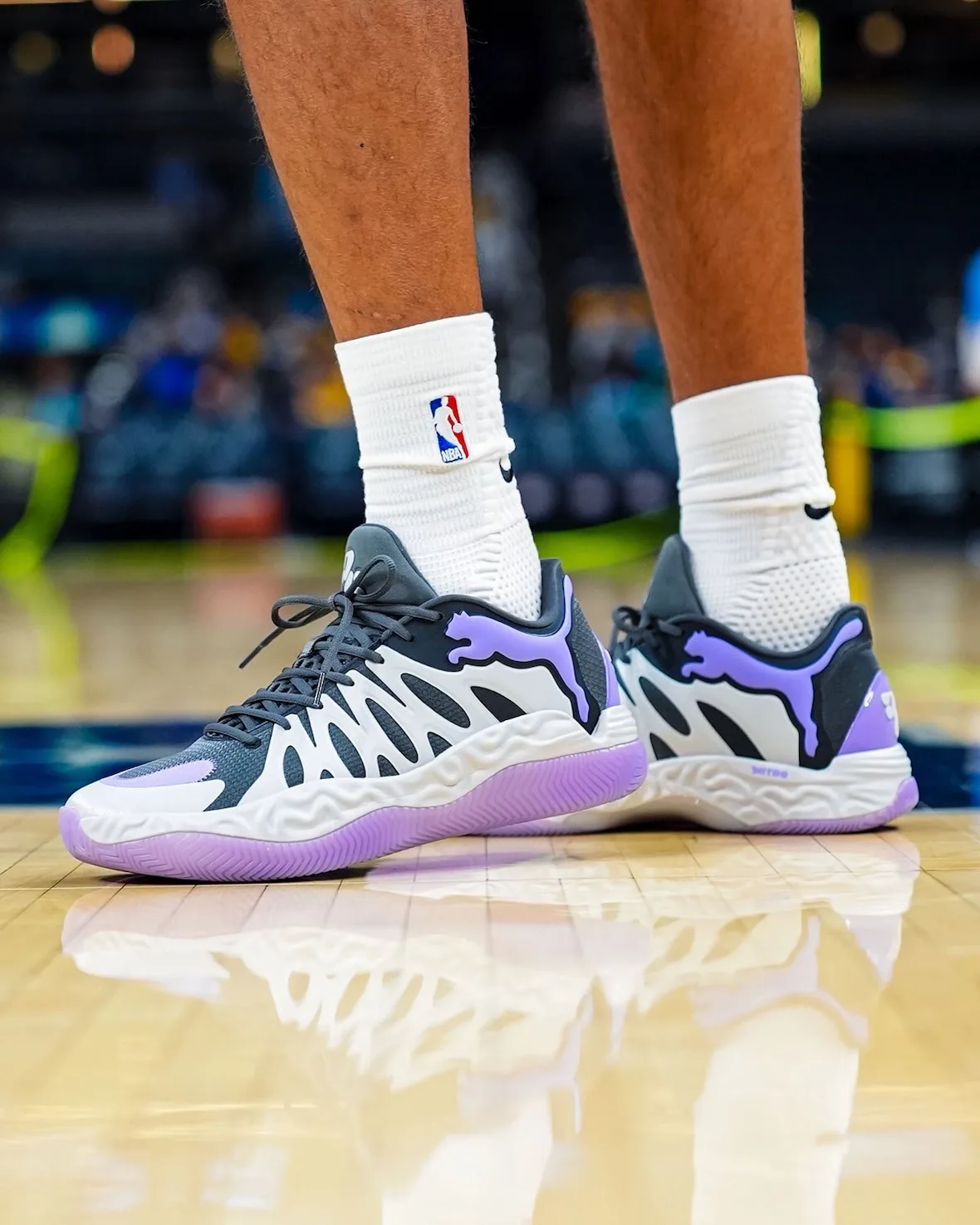 Low on-foot pair view, white and purple sneakers on glossy court with floor reflection, Teddy Lockart