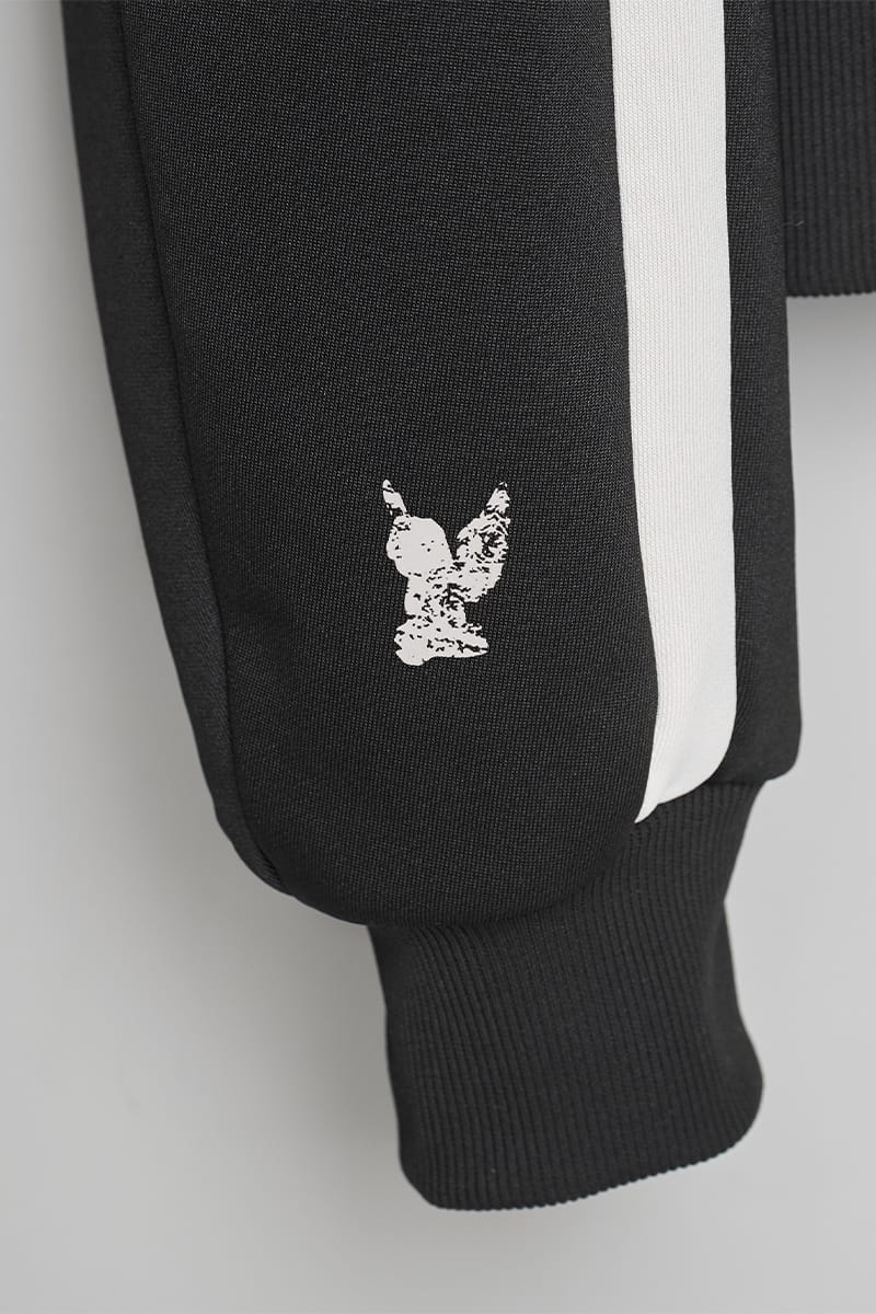 Close-up of black jacket sleeve with cream stripe, small cream bird print, ribbed cuff, IVORYxBLACK