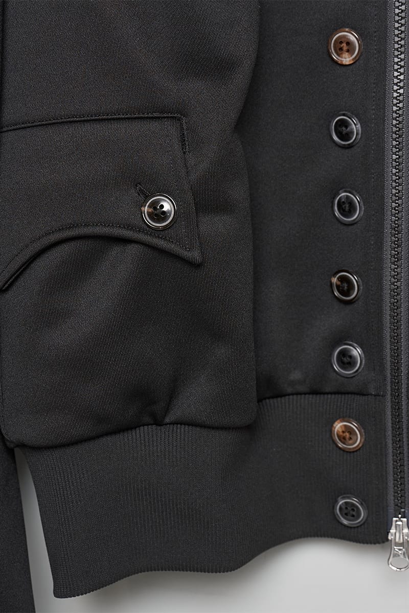 Close-up of black jacket pocket and button placket with horn-style buttons and zip, IVORYxBLACK