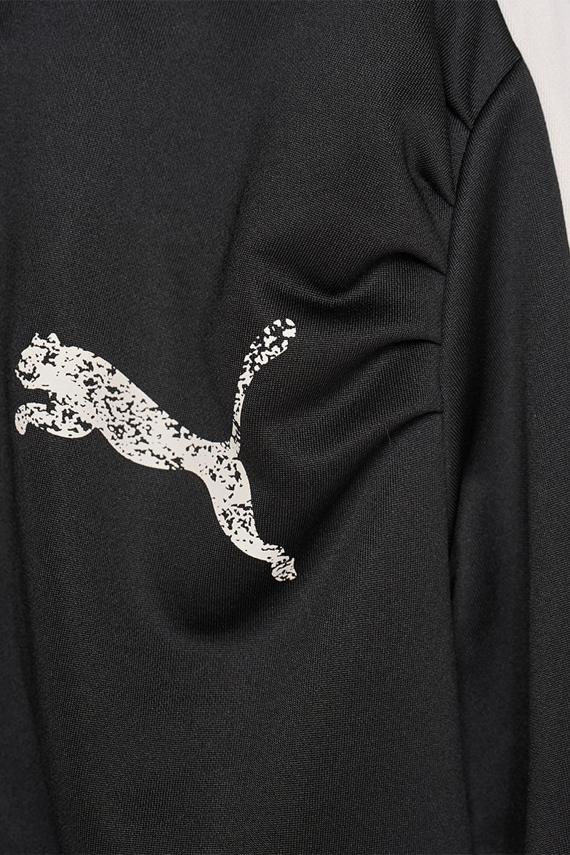 Close-up of black jacket chest with cracked cream cat logo and gathered shoulder fabric, IVORYxBLACK