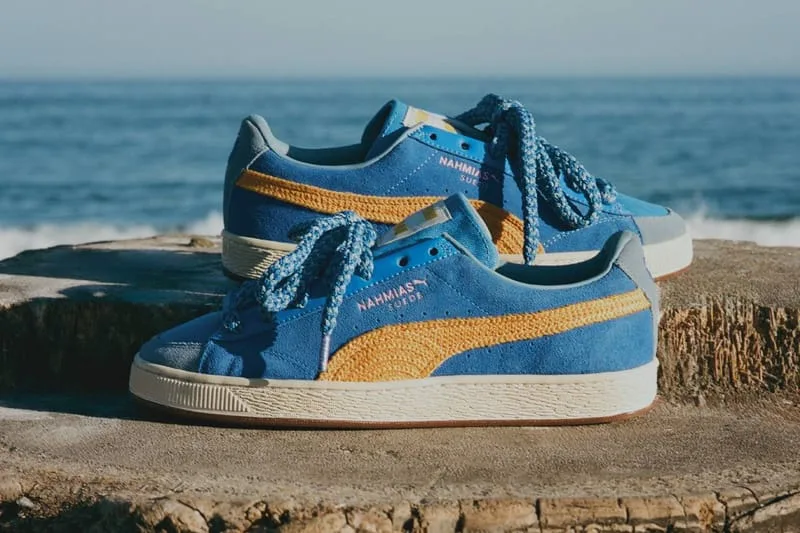 Lateral view of blue suede pair with yellow crochet stripe and blue laces on a stump by the sea, NAHMIAS Suede Crochet