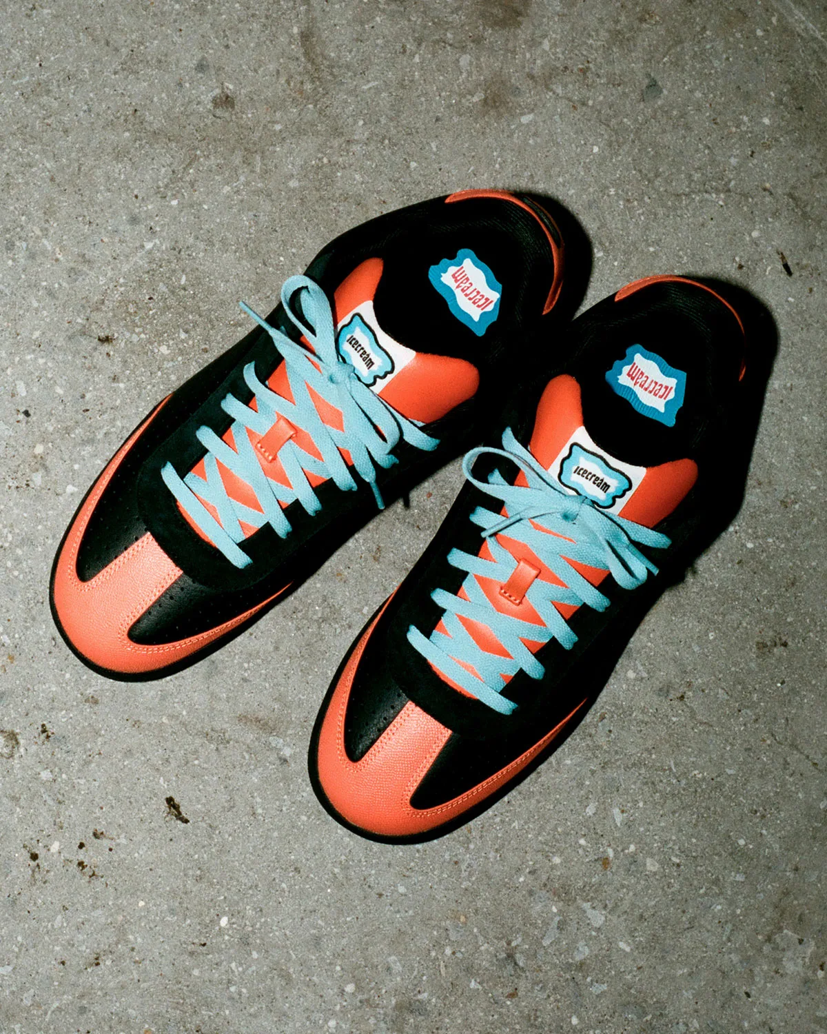 Angled top-down pair on concrete, orange toe caps, black perforated panels, light blue laces and icecream labels, Pumpkin