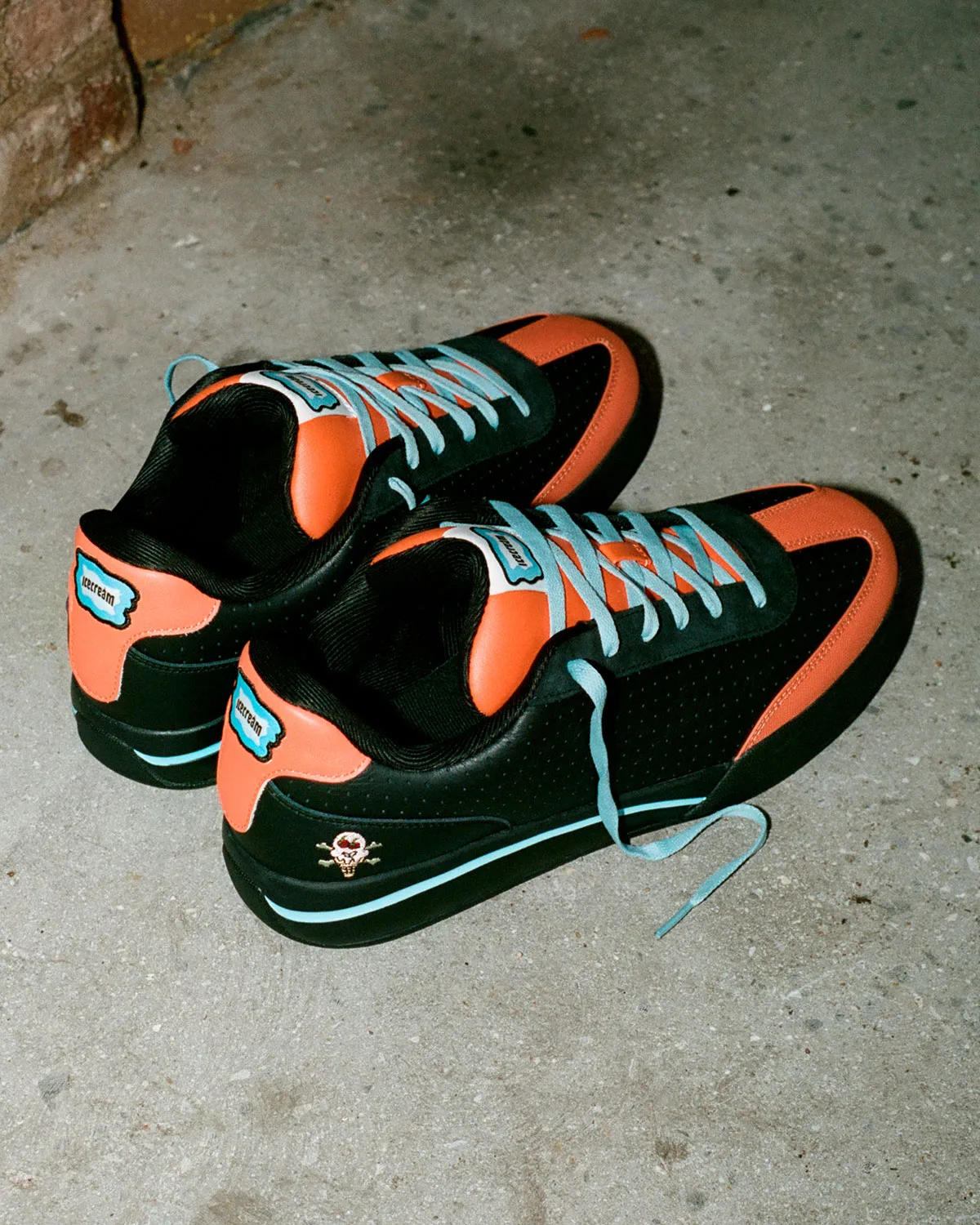 Pair from heel side on concrete, orange heel tabs with icecream patches, light blue midsole stripe, skull logo, Pumpkin