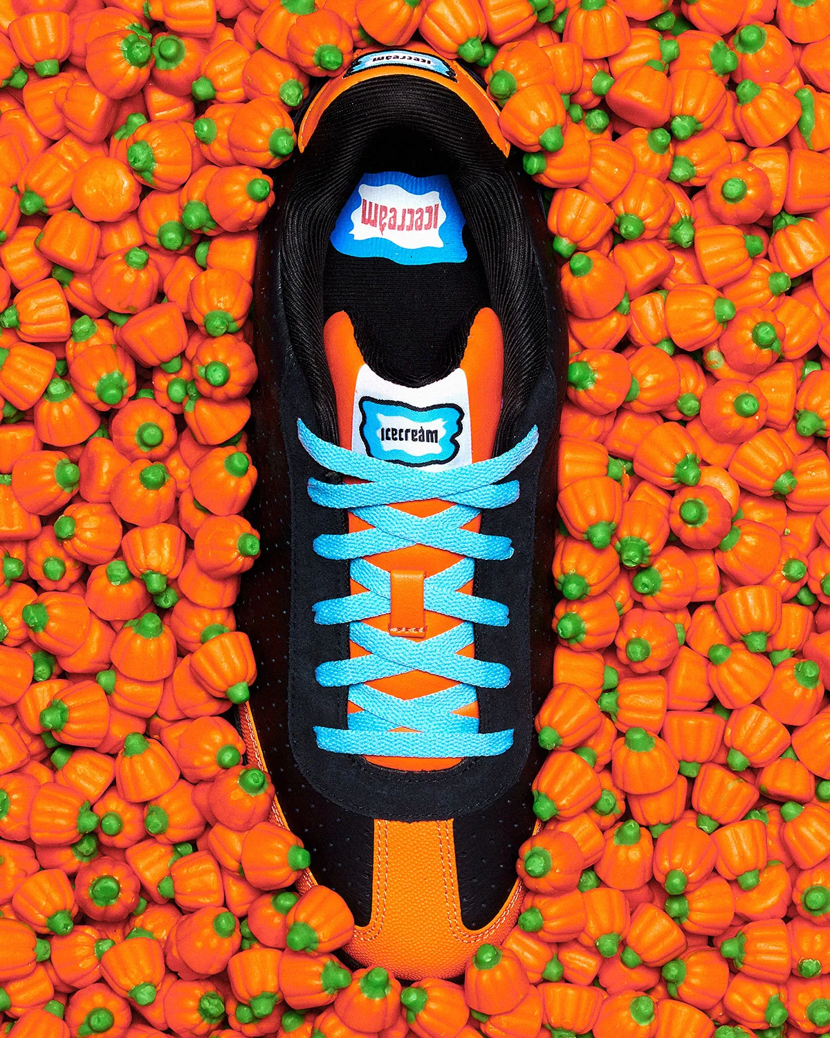 Top-down shoe surrounded by orange and green candy pumpkins, black upper, bright blue laces, icecream tongue label, Pumpkin