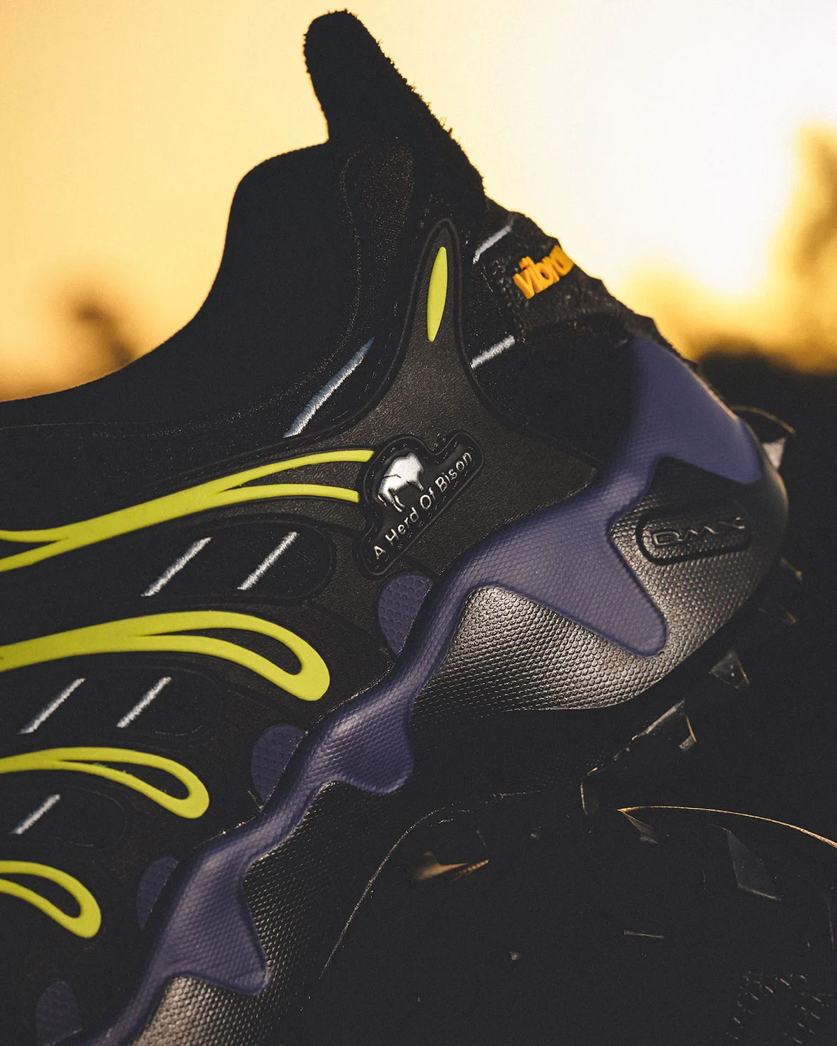 Detail of heel and midsole at sunset, A Herd of Bison badge, purple midsole, orange Vibram logo, Reebok DMX Trailzilla