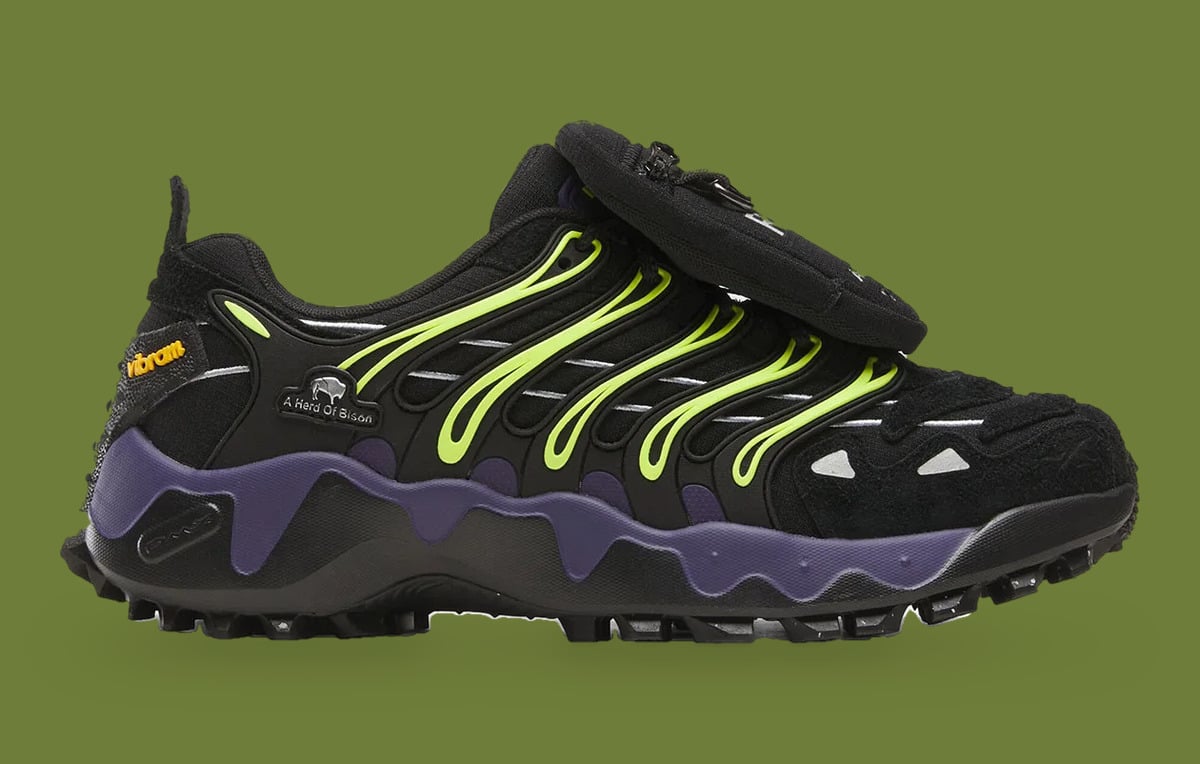 Lateral view on green backdrop, black upper, neon yellow ribs, purple midsole, flap pocket, Reebok DMX Trailzilla