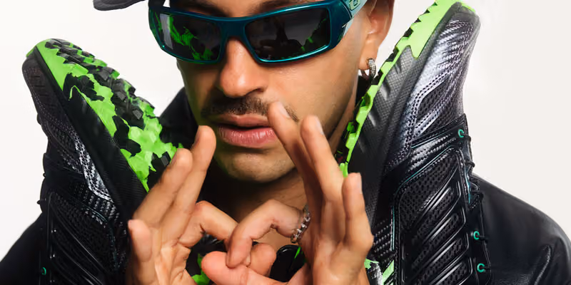 Feid wearing dark green sunglasses with black and neon-green Salomon shoes beside his face