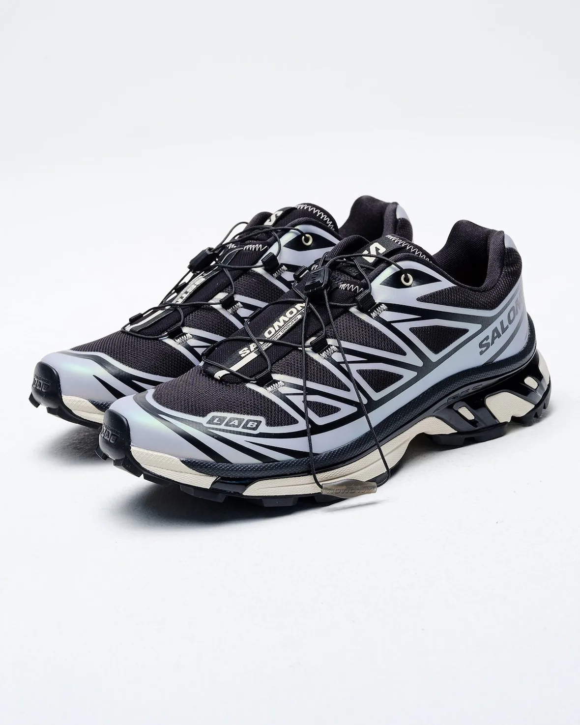 Pair angled front three-quarter, lilac-grey overlays, black mesh, cream midsole, white backdrop, 5 AM