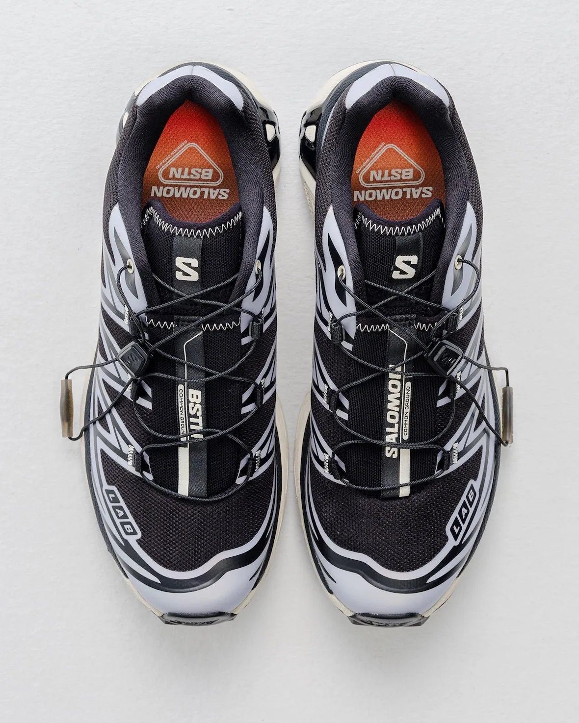 Top-down pair, orange-red BSTN Salomon insoles, black bungee laces, LAB badges, 5 AM
