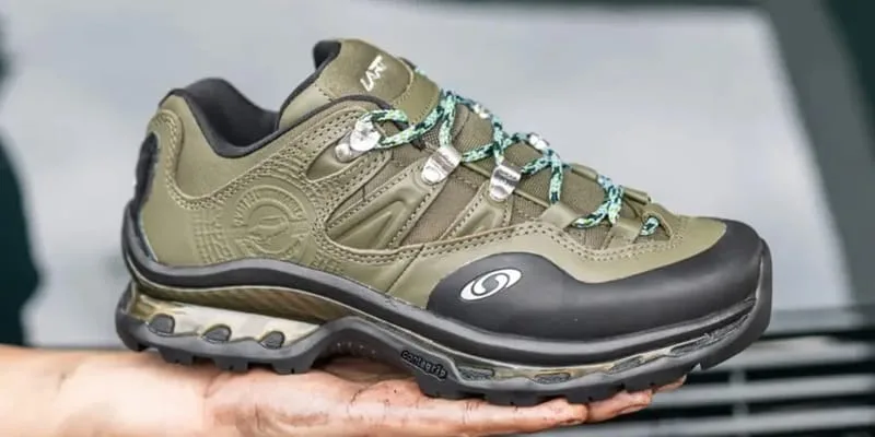 Lateral in-hand view of olive sneaker with black toe cap, Salomon logo, Salomon XT QUEST 2 x L’Art de L’Automobile “Olive”