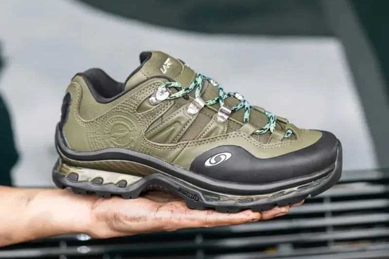Lateral view held on a palm, olive upper, black rubber toe, silver lace hooks, patterned laces, Olive