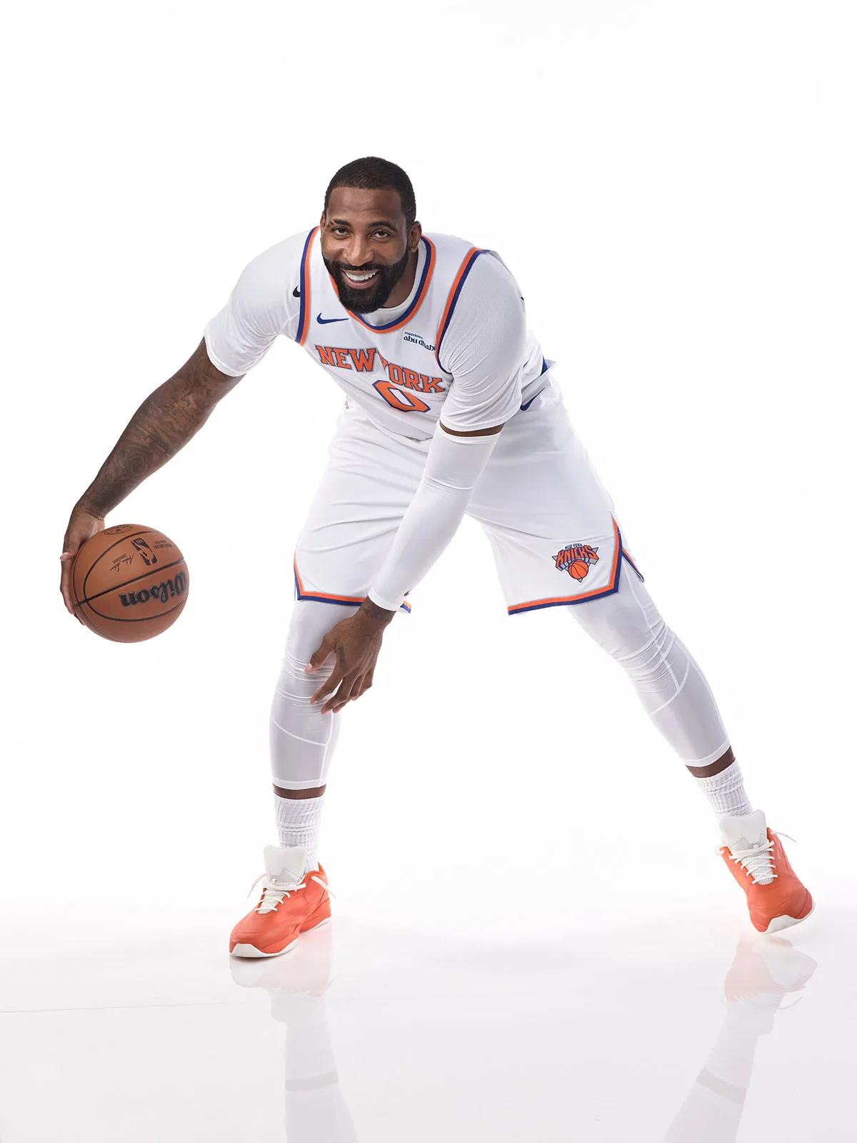On-foot studio shot of a player dribbling, bright orange sneakers with white laces, white jersey, white backdrop, Sport