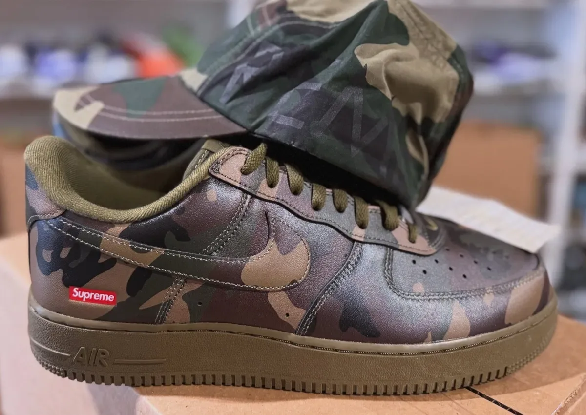 Lateral view of camo leather sneaker with olive sole and red Supreme tag, camo, Supreme x Nike Air Force 1 Low “Olive Camo”