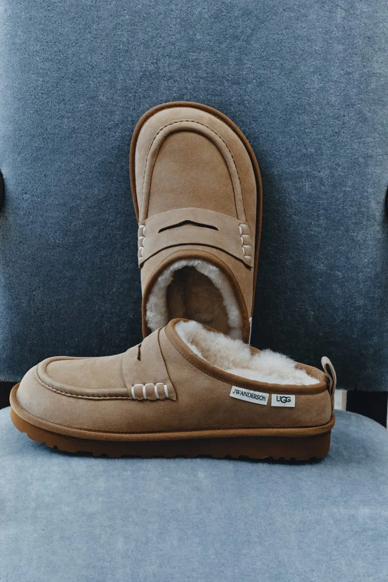 Pair of tan suede loafer clogs on a blue-grey chair, JW Anderson and UGG labels on the heel and shearling inside, x JW
