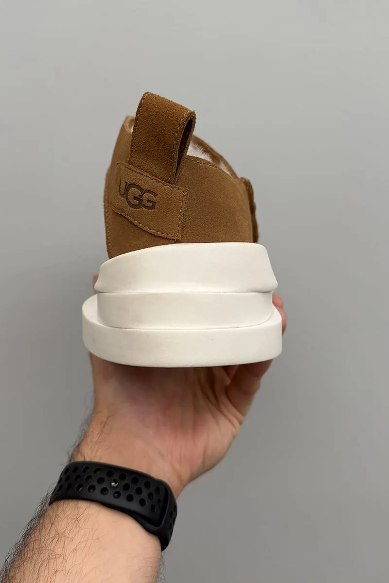 Heel view held in hand showing tan suede UGG heel tab, pull loop and stacked white sole, Heritage Utility Grizz