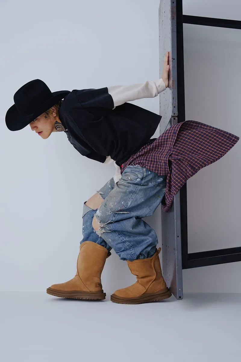 On-foot side view of model leaning in cowboy hat and ripped jeans wearing tan suede boots, Heritage Utility Grizz