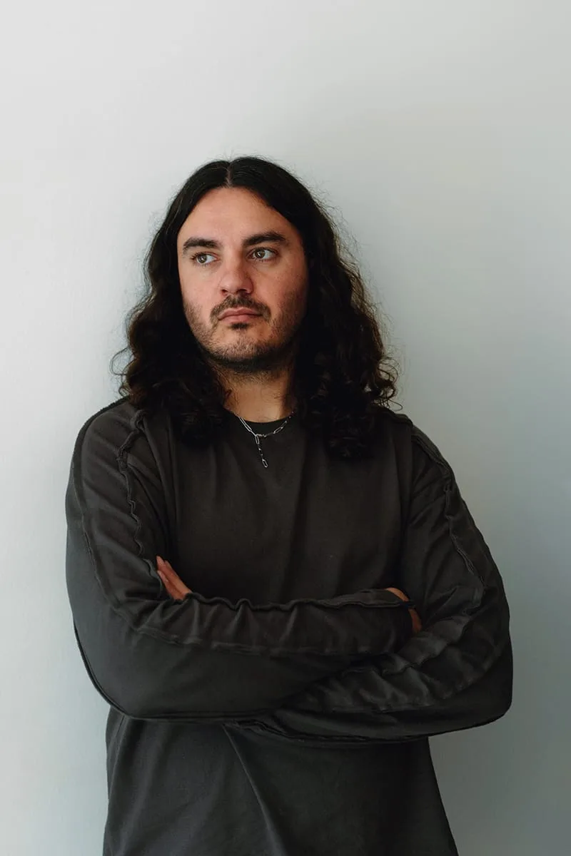Portrait of a long-haired bearded man in a dark sweatshirt with arms crossed, not the product, Heritage Utility Grizz