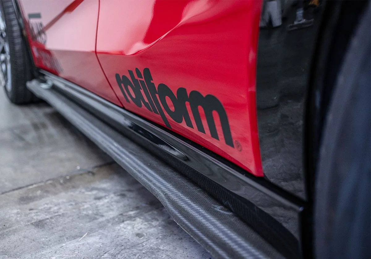 Low detail of red car side with black rotiform lettering above carbon side skirt, x Coco Zurita