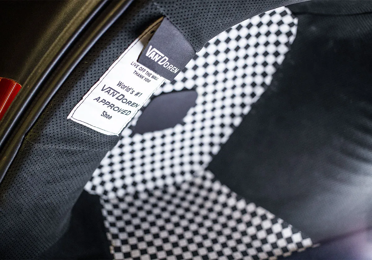 Detail of white tag reading Live off the wall beside black and white checkerboard lining, x Coco Zurita