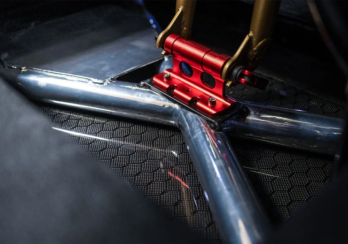 Detail of red bike fork mount, gold fork legs and polished metal tubes in car floor, x Coco Zurita