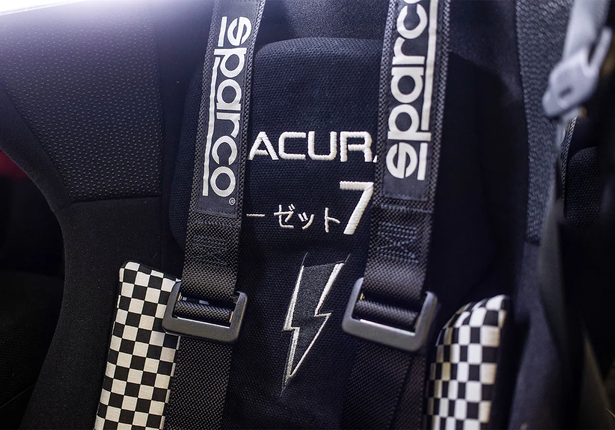 Detail of black racing seat with Sparco harness straps, checkerboard pads and lightning bolt, x Coco Zurita
