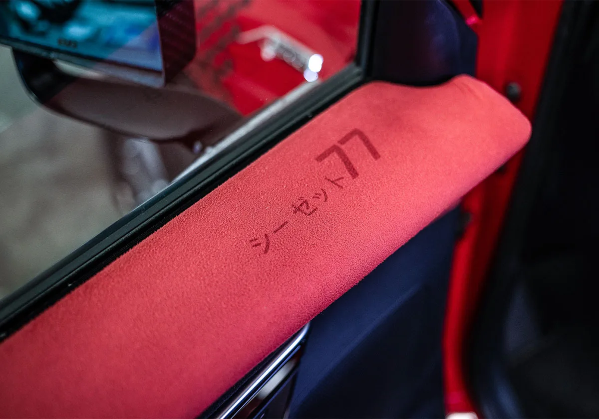 Detail of red suede door armrest with debossed Japanese characters and 77, x Coco Zurita