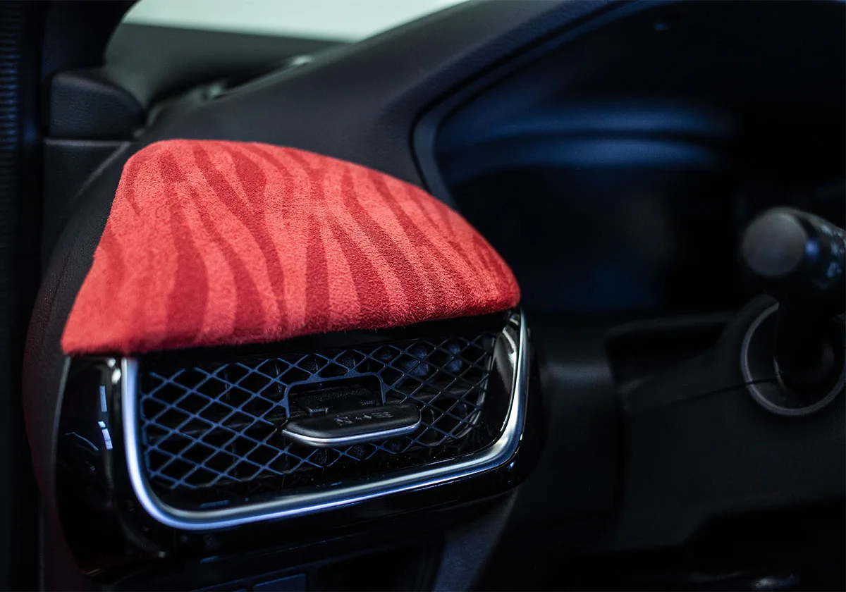 Detail of red zebra-striped suede dash trim above a mesh air vent, x Coco Zurita